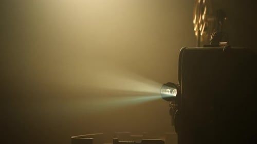 Oude filmprojector werpt een lichtbundel door een donkere ruimte