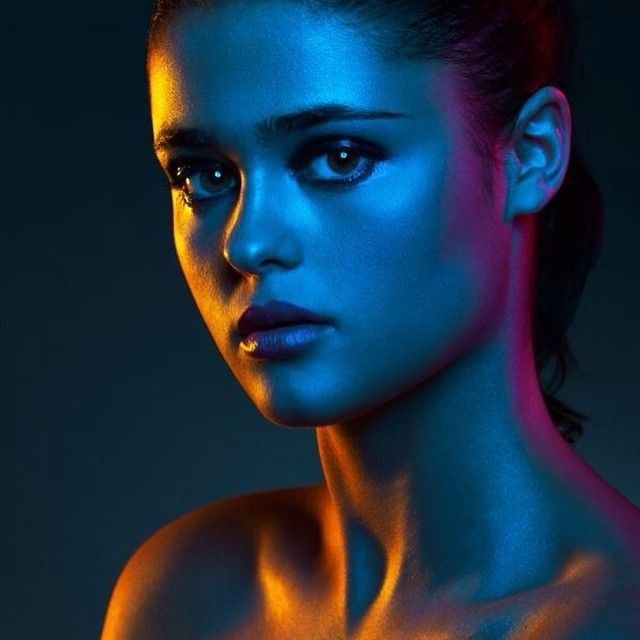 Portret van een vrouw in contrasterend blauw, oranje en roze licht